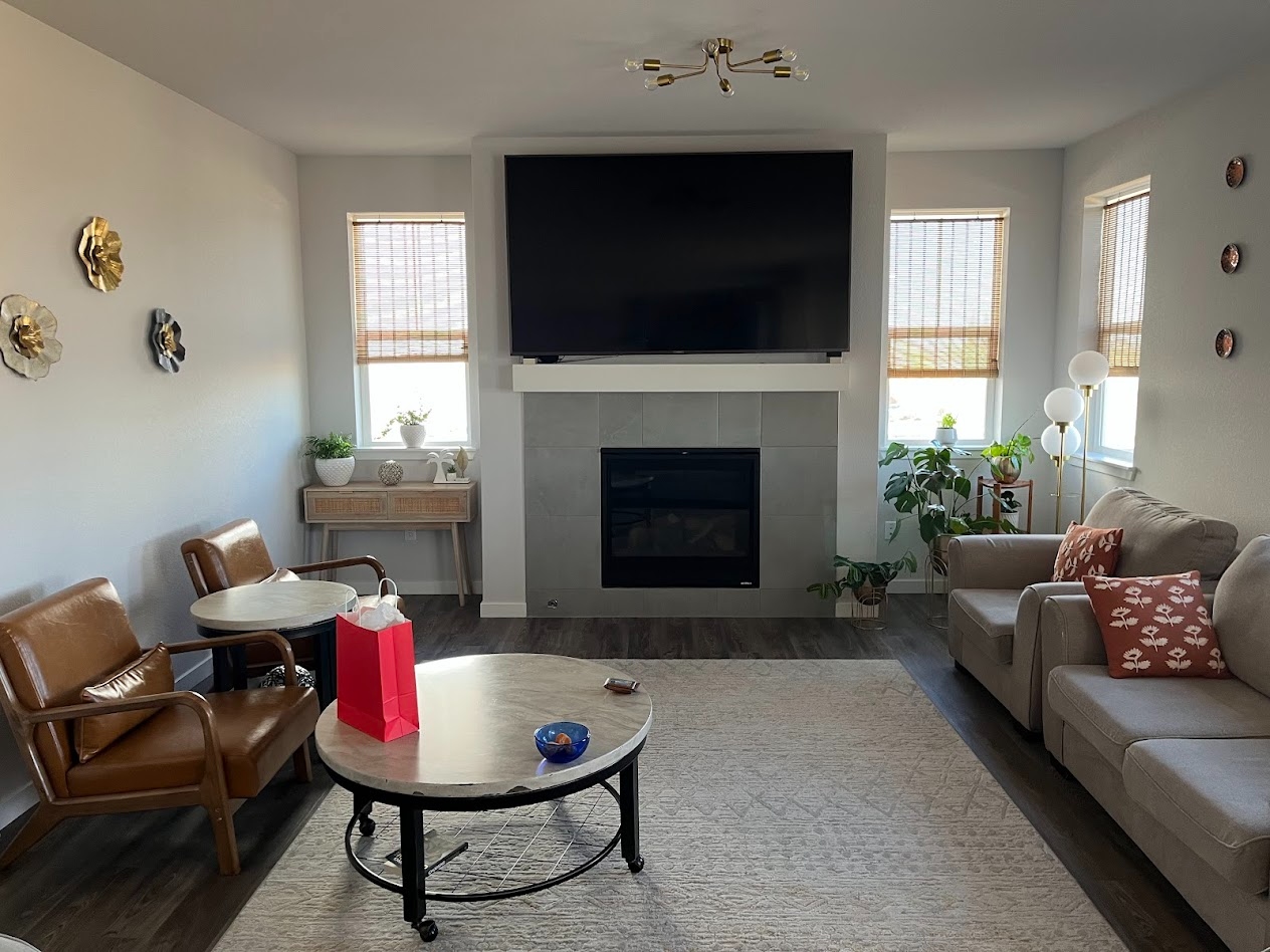 Living room with fireplace, mounted television, and soft neutral seating